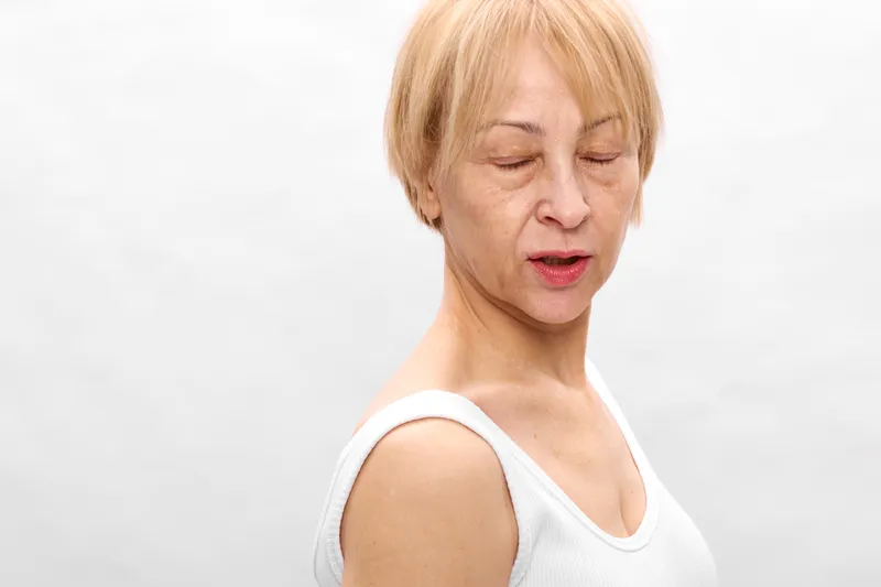 Woman with short blonde hair in a studio closeup, eyes closed in relaxation. White background emphasizes calm face expression. Concept of wellness and selfcare for healthy skin.