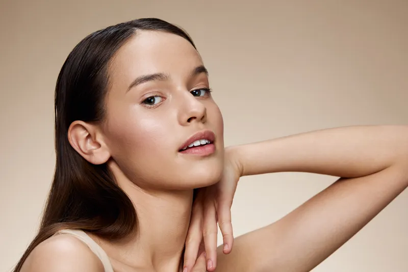 Young woman portrait with natural makeup, soft expression, and neutral background showcasing beauty and confidence