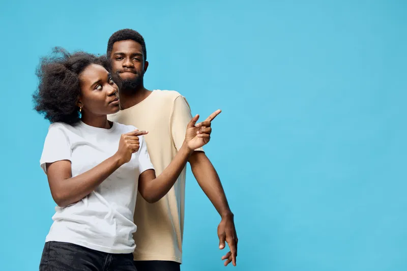 Young African couple joyfully dancing against a bright blue background, showcasing vibrant emotions and playful gestures, perfect for summer themes