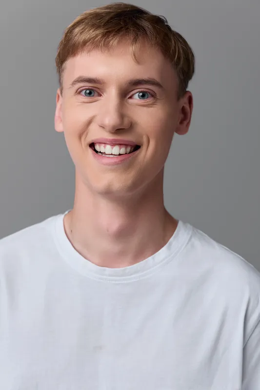 Man, smiling, casual, white t-shirt closeup for lifestyle and fashion stock image focused on everyday style, friendly expression, clean studio background, approachable vibe
