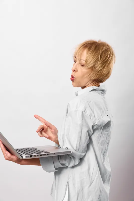 Woman with laptop in side profile, typing thoughtfully, business office communication, white background, focused expression, modern technology, soft clean light