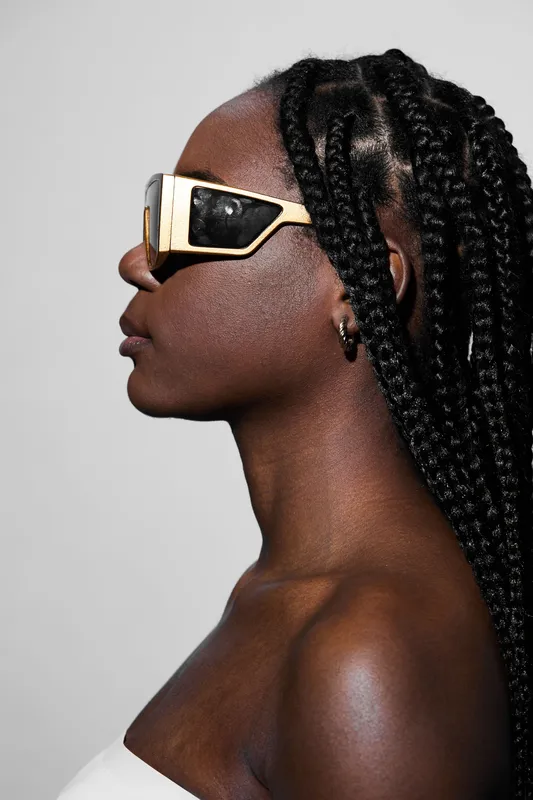 Stylish black model with braided hair wearing oversized sunglasses, showcasing a modern and urban vibe against a neutral background