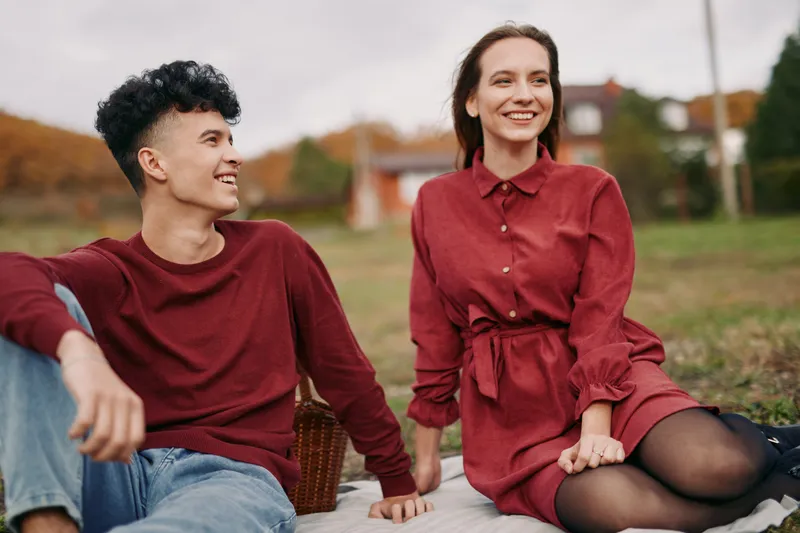 Candid outdoor portrait of a smiling couple sharing a relaxed picnic on a blanket, capturing authentic connection and natural interaction in a warm, trustworthy moment