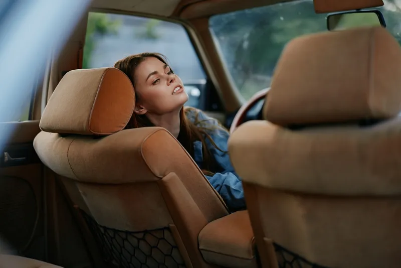 Young woman enjoying a moment of relaxation in a vintage car, with a serene expression, wearing casual denim attire, highlighting vintage aesthetics and a nostalgic vibe.