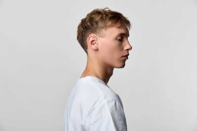Man profile side view white shirt studio minimal composition showing calm modern silhouette with clean lines and neutral background for fashion and lifestyle use