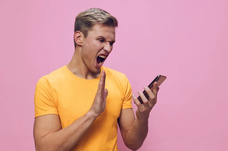 angry man wearing yellow t-shirt scream hold smartphone frustrated cyber security concept isolated pink background