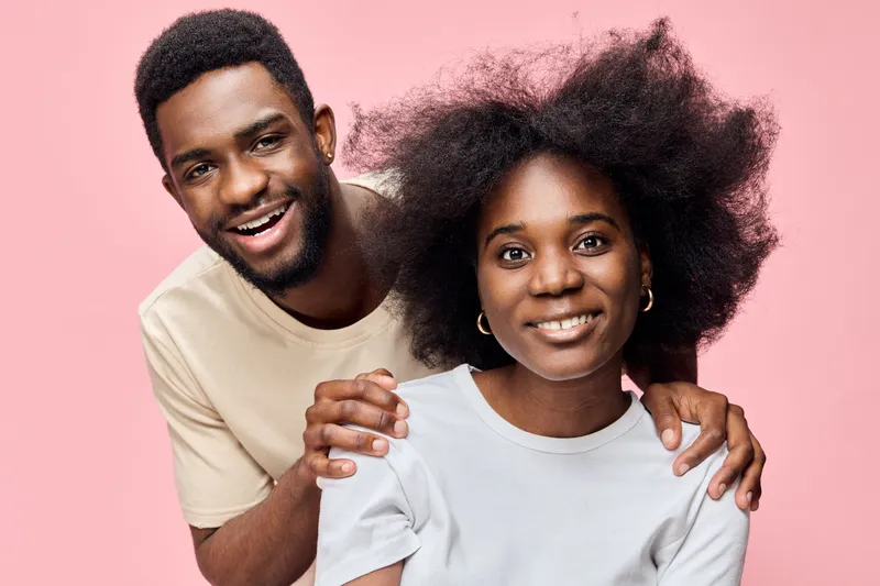Joyful African American couple with natural hairstyles on a pink background, showcasing happiness and love, perfect for lifestyle and relationship themes