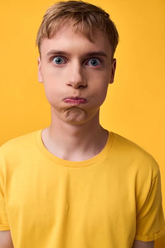 Boy with a pout against a bright yellow background, showing facial expression and emotion, bold color contrast for playful, design driven stock photography and expressive lifestyle imagery