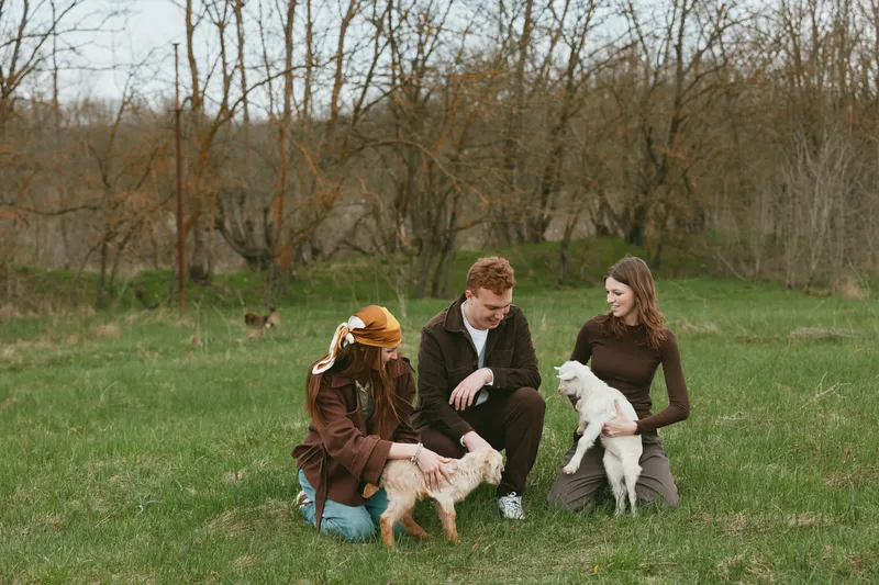 Goat kid lifestyle outdoor scene with friends in a park, featuring a friendly animal and pet companionship, as nature sunlight and smiles capture joyful interaction and warm togetherness.