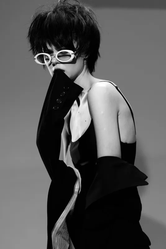 Stylish woman wearing white sunglasses and a black off-shoulder outfit in black and white fashion portrait