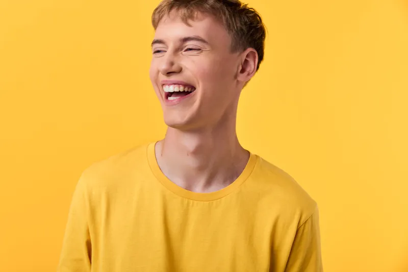 Smile, happiness, laughter, yellow shirt, studio setting, cheerful and vibrant mood with a smiling model, man, bright casual look, expressive pose, capturing energy and warmth in photography