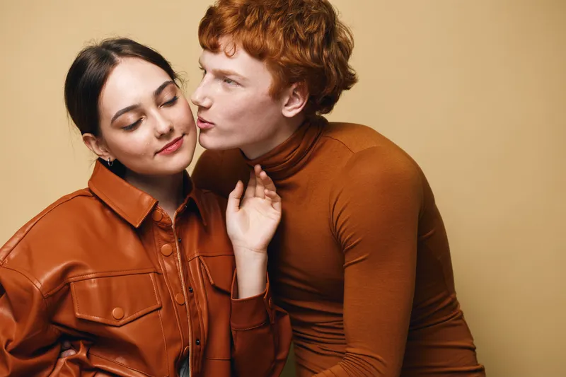 Couple, woman and man with casual fashion, affectionate moment and closed eyes for love and intimacy in studio. Young people in warm clothes showing connection and tenderness.