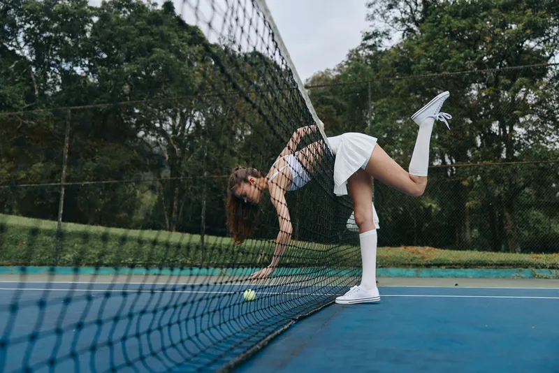Young female tennis player adjusting the net on a beautiful outdoor court, showcasing athleticism and determination in a stylish white outfit, capturing the essence of sports and competition