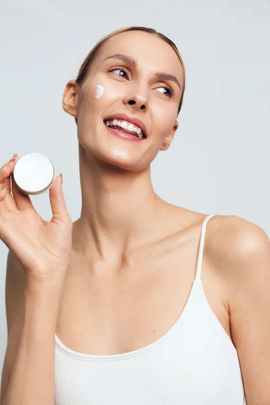 Woman beauty skincare makeup, holding compact powder, smiling in studio, white background, soft light, clean complexion, close up