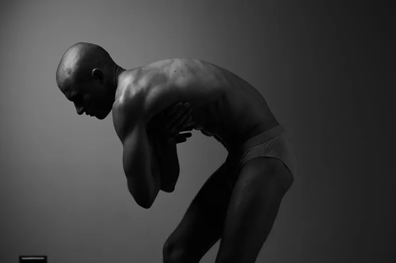 Black and white portrait of a man in an expressive pose, showcasing emotion and artistic form, emphasizing the beauty of the human body in monochrome.