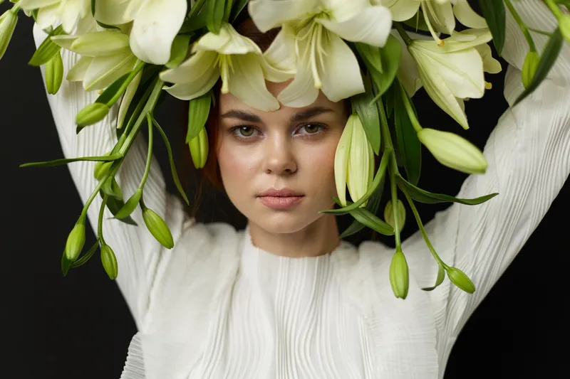 Portrait of a model with white lilies, showcasing emotions of tranquility and elegance against a dark background, emphasizing a floral theme and sophistication