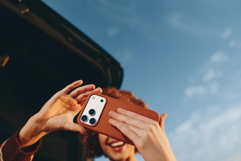 Woman hands hold smartphone for selfie outdoors lifestyle by car, summer sunlight, casual jacket and scarf, closeup smiling portrait, modern communication technology, travel vibe