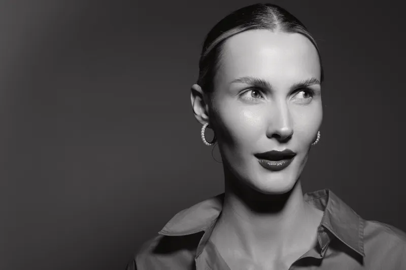Portrait of a fair skinned Caucasian woman with slicked back hair and hoop earrings looking to the side in black and white. Concept of elegance, beauty, and classic style.