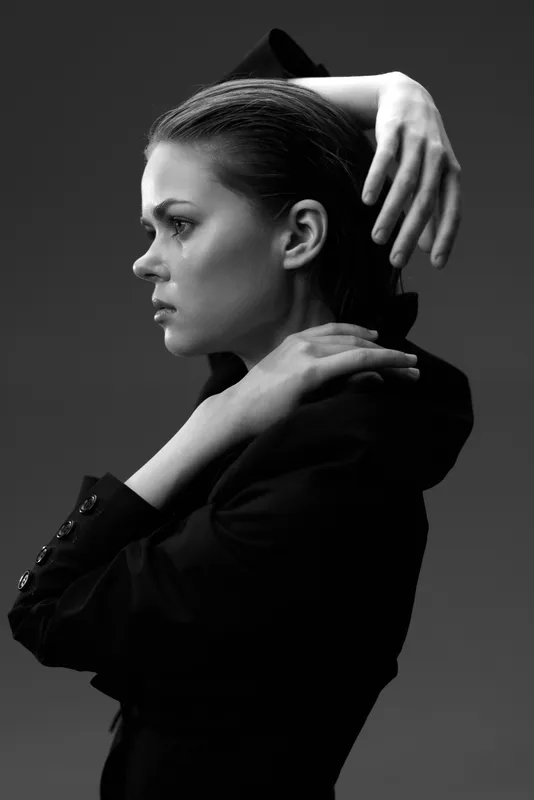 Black and white portrait of a serious young woman in formal attire with a thoughtful expression.