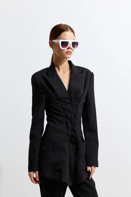 fashion woman wearing stylish black blazer and white sunglasses, posing confidently against minimal white background in modern fashion style