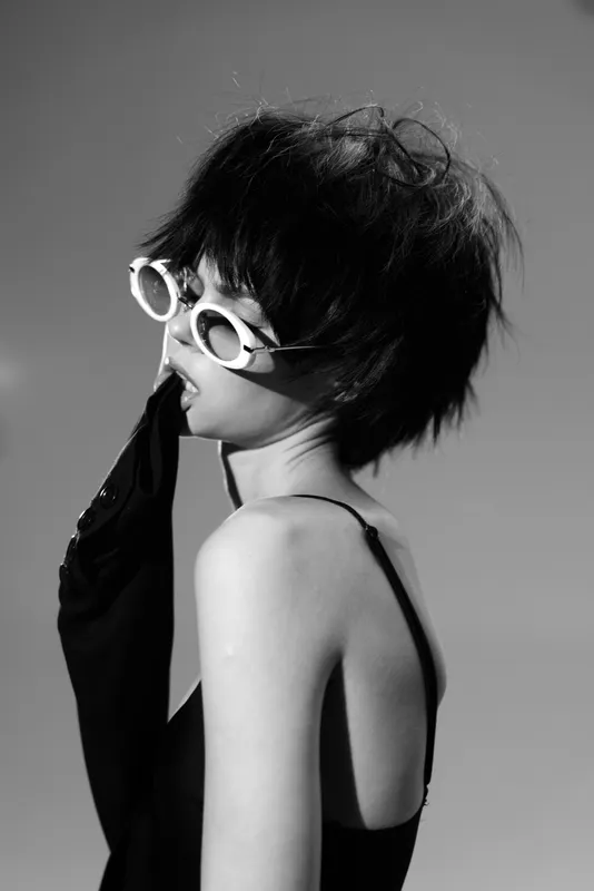 black and white portrait of a woman with short hair wearing sunglasses and a glove, stylish and dramatic mood