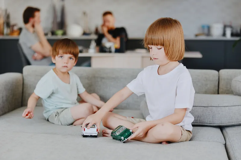 Two young boys playing with toy cars in a cozy living room, showcasing a joyful moment of childhood, creativity, and imagination.