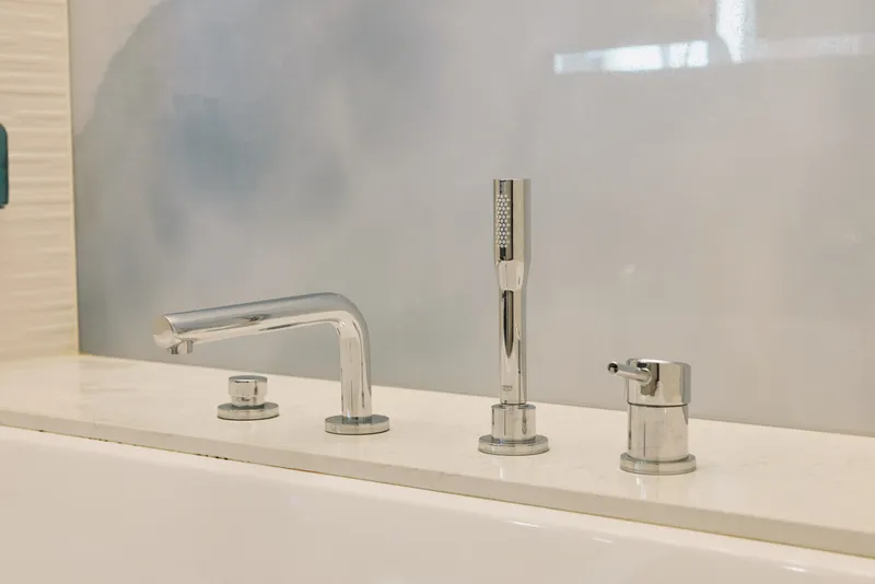 Faucet, sink and chrome bathroom fixtures arranged over a clean counter, water tap highlights modern plumbing design with reflective surfaces and minimalist style in a neat, calm space
