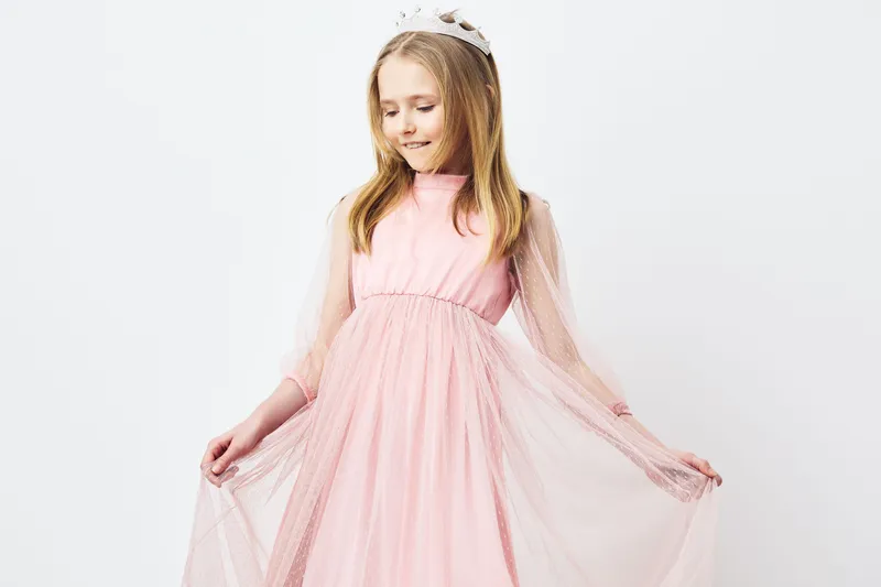 Young girl in a pink dress with a princess crown, showcasing elegance and joy, ideal for children s fashion or celebrations