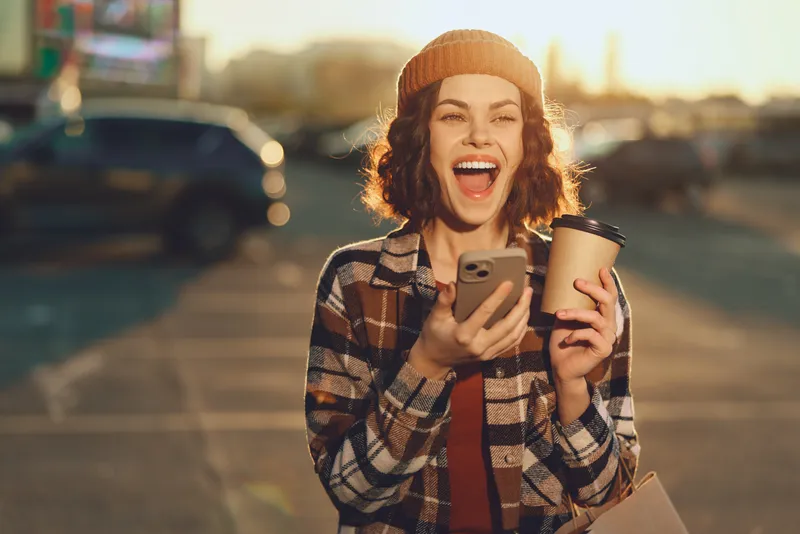 woman coffee smartphone smile candid golden urban lifestyle authenticity and golden hour glow capture mindful living and emotional storytelling in a spontaneous, joyful urban portrait of real joy