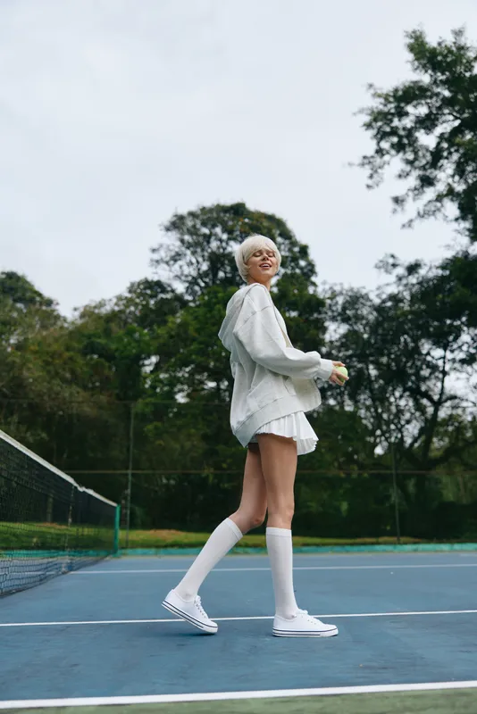 Young female model in sportswear smiling on a tennis court, showcasing athleticism and joy, perfect for healthy lifestyle concepts