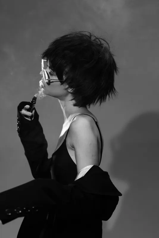 Black and white portrait of a woman with short hair holding a magnifying glass, artistic and moody atmosphere