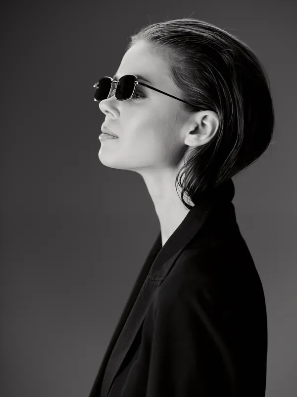 Profile of a stylish woman wearing sunglasses and a black blazer in black and white