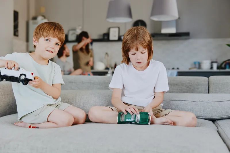 Engaging scene with two boys playing with toy cars in a cozy living room, showcasing childhood joy and creativity in a modern home setting.