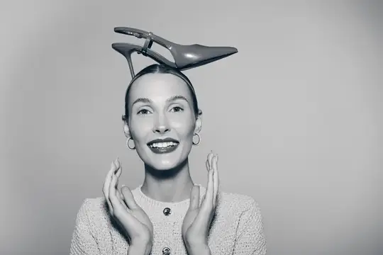 Улыбающаяся женщина с туфлей на голове в студии