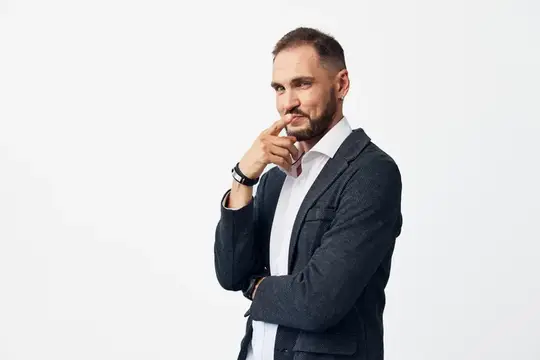 Задумчивый мужчина в пиджаке с рукой у лица на белом фоне