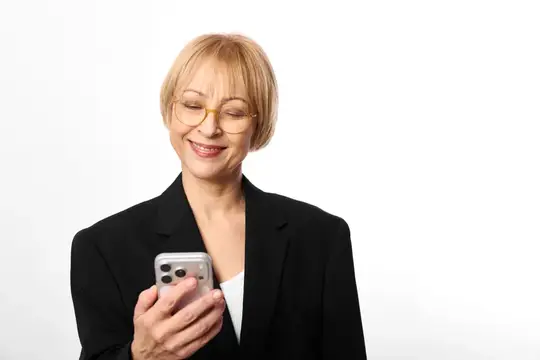 Улыбающаяся блондинка в очках смотрит в смартфон
