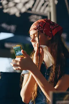 Девушка в красной бандане разговаривает по телефону на улице