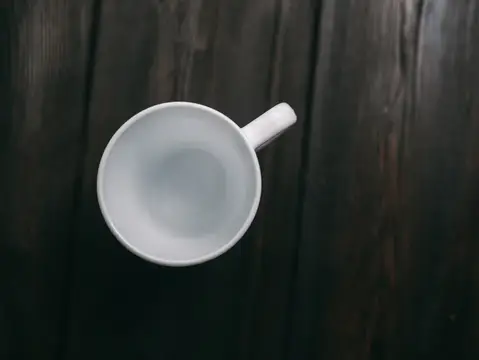 Белая кружка с водой на тёмном деревянном столе
