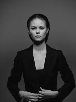 Молодая женщина в строгом чёрном пиджаке на тёмном фоне