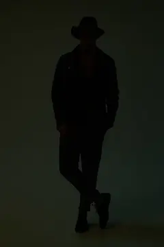 Силуэт мужчины в шляпе и пальто в темноте