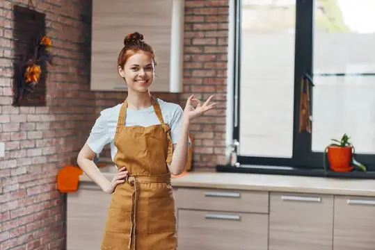 Красивая женщина в коричневом фартуке на кухне