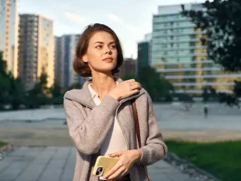 Молодая женщина с телефоном на городской площади в солнечный день