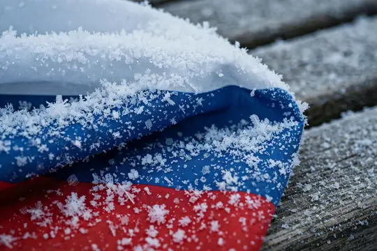 Российский флаг в снегу лежит на деревянной поверхности