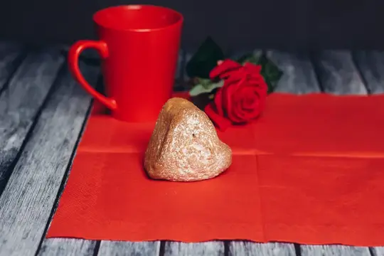 Красная кружка, роза и конфета на салфетке