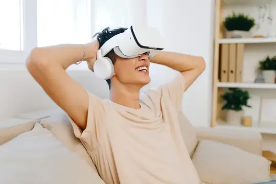Улыбающийся парень в VR-очках отдыхает на диване
