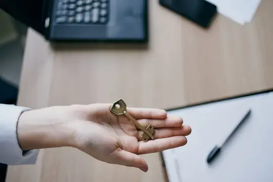 Ключ в руке, символизирующий заключение договора о продаже дома
