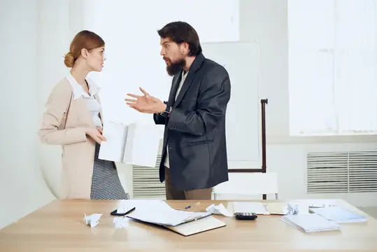 Бородатый мужчина эмоционально объясняет что-то коллеге в офисе