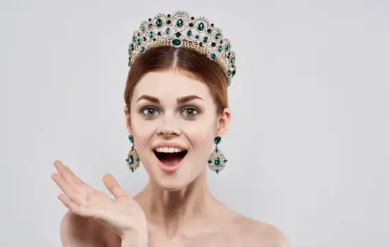 Удивлённая девушка в роскошной короне с изумрудами