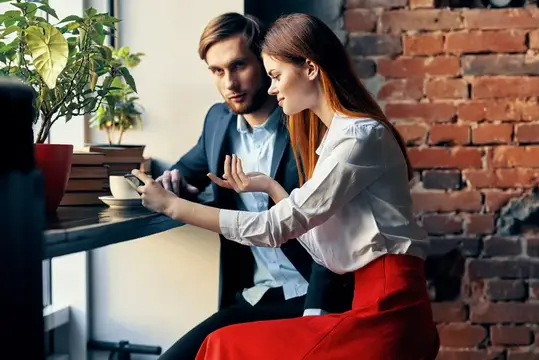 Молодые коллеги обсуждают проект за столиком у кирпичной стены