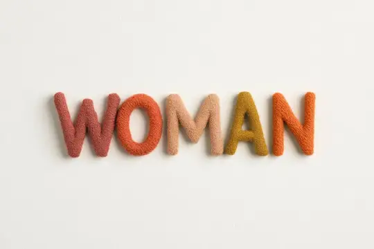 Слово WOMAN из разноцветных шерстяных букв на белом фоне